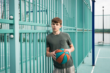 Boy teenager playing basketball at city playground. Active life, hobby, sports for children