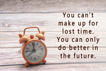 Motivational quote with alarm clock on wooden background