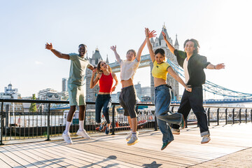 Multiracial group of happy young friends bonding in London city - Multiethnic teens students meeting and having fun in Tower Bridge area, UK - Concepts about youth lifestyle, travel and tourism - obrazy, fototapety, plakaty