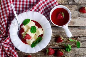 Lazy dumplings with strawberry sauce in a ceramic bowl.