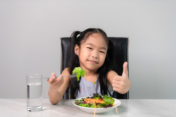 Obraz na płótnie Canvas Little asian cute girl to eat healthy vegetables.Nutrition and healthy eating habits for kids concept.Children happy and like to eat vegetables.