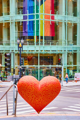 Red love heart art with yellow lines and pride flag in glass building front near Union Square, San...