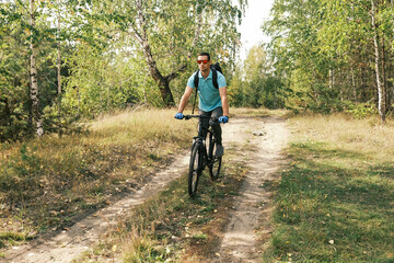 An active lifestyle.A cyclist with a backpack on a mountain bike rides along a forest road in autumn