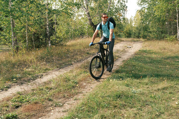 Obraz premium An active lifestyle.A cyclist with a backpack on a mountain bike rides along a forest road in autumn