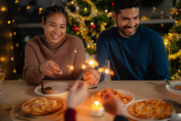 men and women holding sparkler fireworks in a party with Christmas tree. young couple Asian people enjoy celebrating Christmas and New Year. happy and celebrate with food wine and friendship for love,