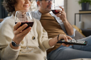 Couple drinking red wine and watching TV while resting on sofa in the living room