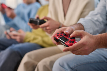 Close-up of family using joysticks to play video game together at home