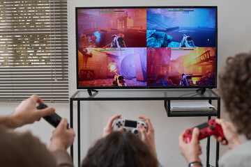 Rear view of family of three using joysticks to play video game on TV at home