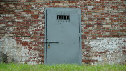 Locked iron door in red brick wall of prison