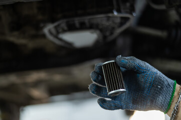 A mechanic replaces the fine filter for the transmission oil. Car on a lift in a car service...
