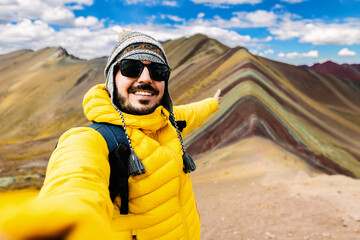Happy young man enjoying travel vacation in Peru, South America. Joyful male tourist taking selfie portrait on Vinicunca or Rainbow Mountain at Cuzco Region.