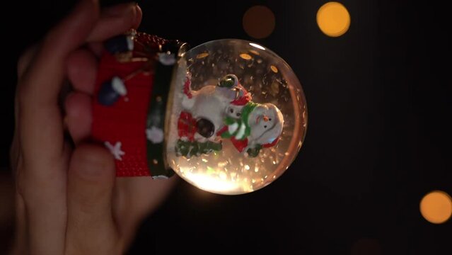 Cristal snow globe. Glass ball toy. Winter traditional snow symbol.  Woman hand holding Christmas symbol. Slow motion vertical reel video footage. hand held camera