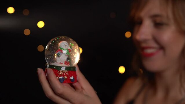 snow globe Christmas and new year winter time symbol. happy blonde woman holding Christmas symbol Cristal ball and smiling. Slow motion video footage. hand held camera. Traditional decoration toy