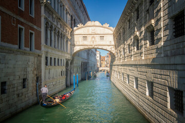 Fototapeta na wymiar un couple dans une gondole s'approche du pont des soupirs à Venise en Italie par une journée ensoleillée sous un beau ciel bleu.
