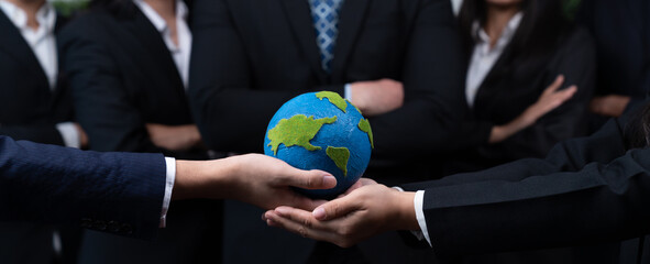 Top view business people holding Earth together in synergy as team building to utilize eco...