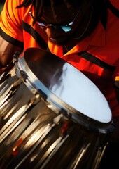 Drummer at a Caribbean Carnival, rhythmically beating a steel drum adorned with bright ribbons