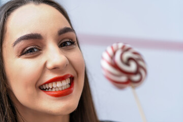 A woman holding a lollipop with a smile on her face. The Joyful Woman with a Sweet Lollipop