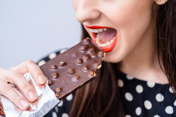 A woman eating a chocolate bar with her mouth open. Indulging in Sweet Pleasure: Woman Delighting in a Mouthwatering Chocolate Bar
