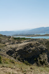 A reservoir against the backdrop of mountains with azure water on a sunny day peaks in a haze.