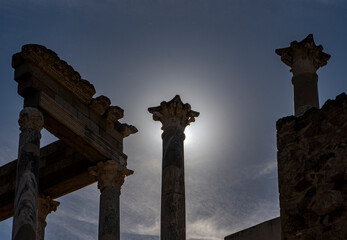 Backlit silhouette with the capital of a column blocking the light of the moon as if it were a lunar eclipse from the ruins of the Roman theater in Mérida, creating a divine glow or shine. - obrazy, fototapety, plakaty