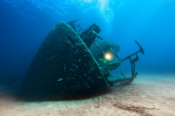 Scuba diver with underwater light around wreck.
