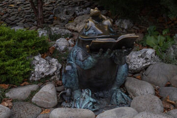 Kharkiv, Ukraine. - November 11, 2023: there are small sculptures in the central park. here a frog is sitting on the stones with a book