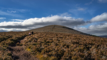 Mother and daughter walking on trail between heather to climb Maulin Mountain. Family hiking in Wicklow Mountains, Ireland
