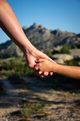 una madre sosteniendo la mano de su hijo, con una montaña al fondo