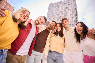 Portrait large group multiracial friends posing smiling to camera. Happy young people hugging...
