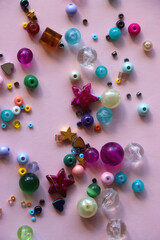 Various colorful beads on bright pink background. Top view.