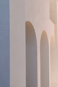 View at a modern white spanish building with arches in sunlight, minimalistic style photography
