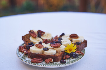 Homemade banana bread with slices of fresh banana, pecan halves or nuts and dried cranberries served on plate as a breakfast, full of energy and with balanced nutritions ideal for healthy lifestyle.
