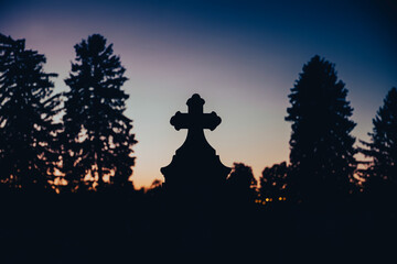 Silhouette of tombstone cross at evening