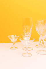 Empty crystal glasses in front of yellow background.