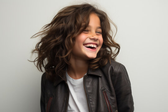 Charming little girl wearing leather jacket with bright smile. This image can be used to showcase fashion, youth, happiness, or coolness