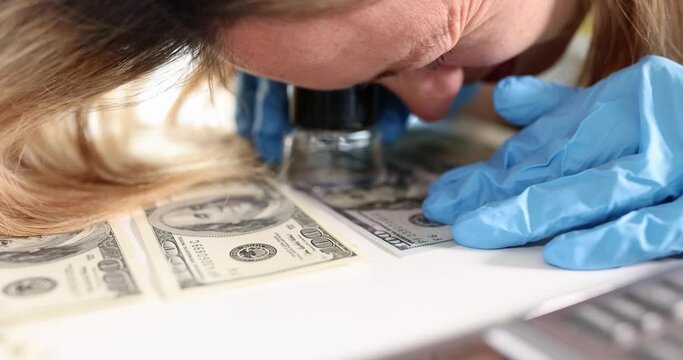 Woman expert looking at money through magnifying glass 4k movie slow motion. Money examination concept