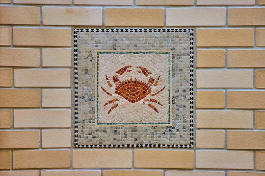 Colorful crab mosaic art tiles with abstract animal crustacean image on yellow brick wall
