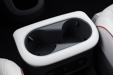 Cup holders of a modern electric car. White leather interior modern electric car. Opened car USB...