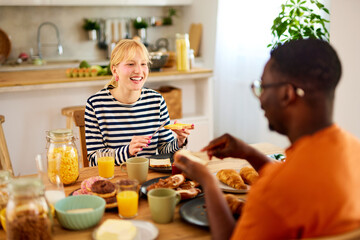 Multiracial couple enjoying breakfast together at home