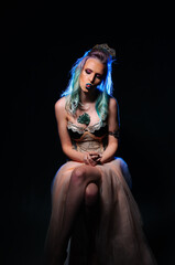 A woman with blue hair sitting on a chair. A Captivating Portrait of a Woman with Vibrant Blue Hair Sitting Serenely on a Chair