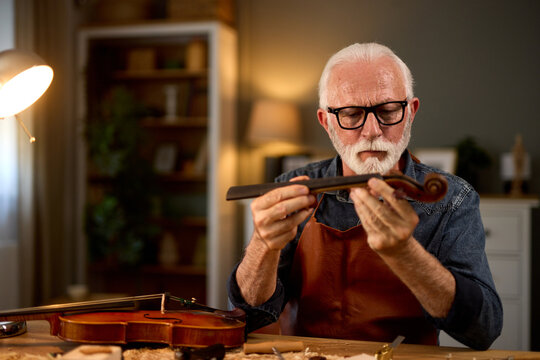 Senior carpenter craftsman carving wood and making violin instrument