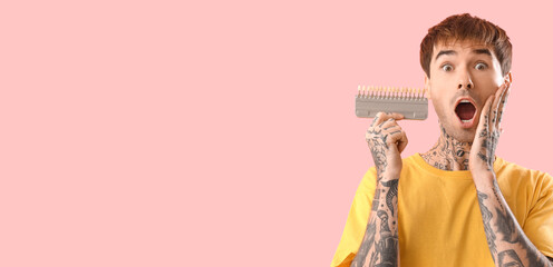Shocked young tattooed man holding teeth color samples on pink background with space for text