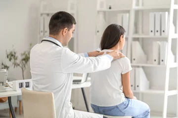 Fotobehang Male doctor checking posture of young woman in clinic © Pixel-Shot