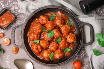 Frying pan of tasty meat balls with tomato sauce and parsley on grey background