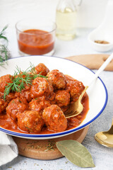 Bowl of tasty meat balls with tomato sauce and dill on white background