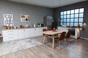Interior of modern kitchen with white counters, dining table and fridge