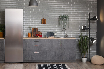 Interior of modern kitchen with grey counters, fridge and houseplants