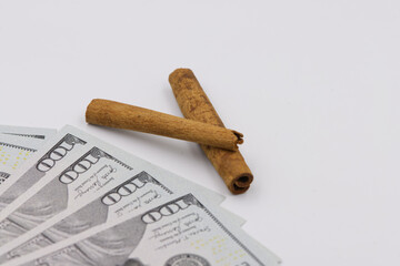 Two pieces of cinnamon bark on the background of one hundred US dollars, cinnamon price concept.