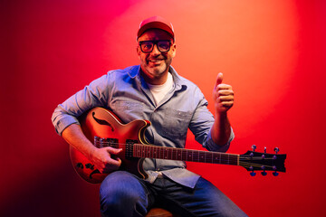 Obraz premium Man playing electric guitar on red background