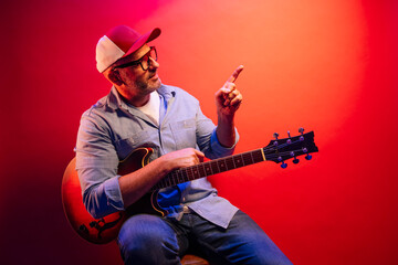 Obraz premium Man playing electric guitar on red background